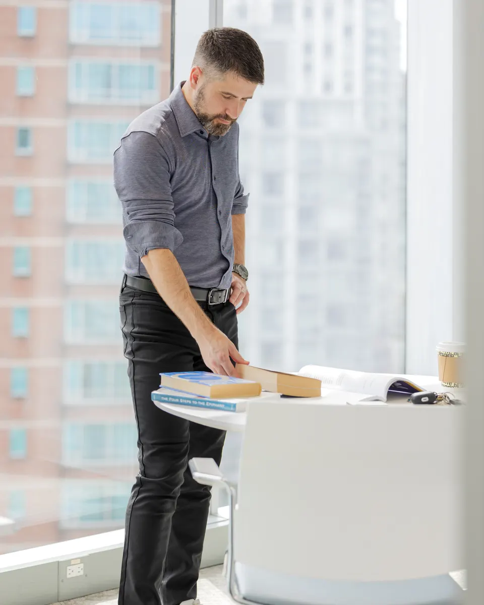 Abel Osorio at a standing desk in Vancouver, reading over an open book